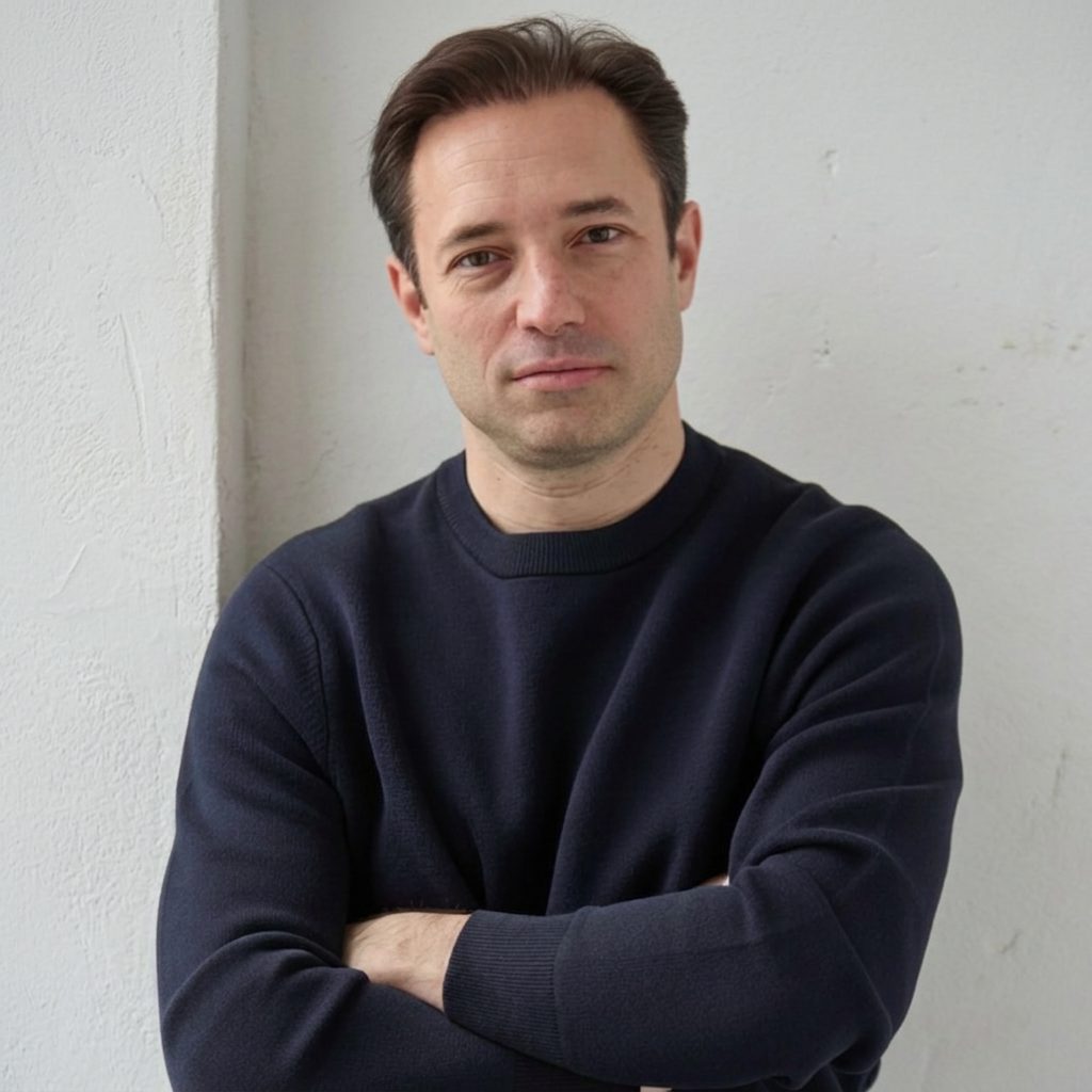 Mathieu Bonnefont standing against a white wall, arms folded